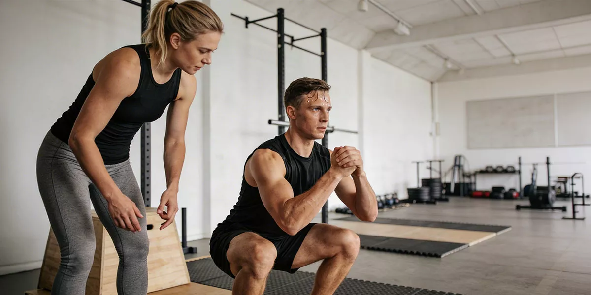 Ein Mann macht eine Übung beim Personal Training mit seiner Trainerin in einem hellen Studio