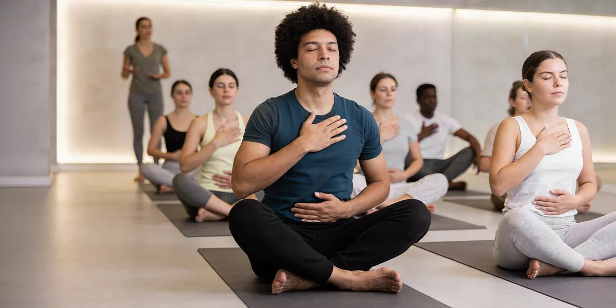 Eine Gruppe sitzt mit geschlossenen Augen auf Matten beim Breathwork