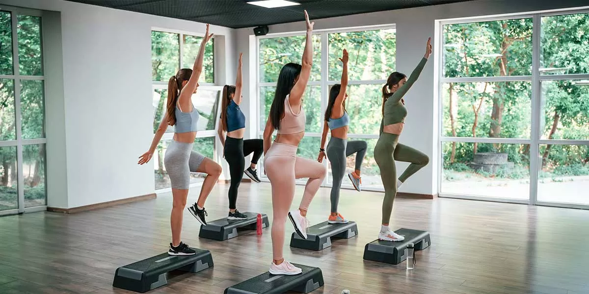Eine Gruppe von Frauen beim Step Aerobic auf Steps in einem Studio mit großen Fenstern