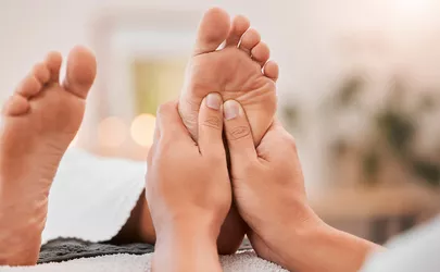 Eine Nahaufnahme von Händen bei einer Fußreflexzonenmassage