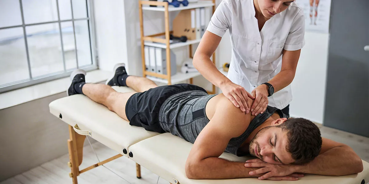 Ein Mann in Sportkleidung bei einer Sportmassage auf einer Massagebank